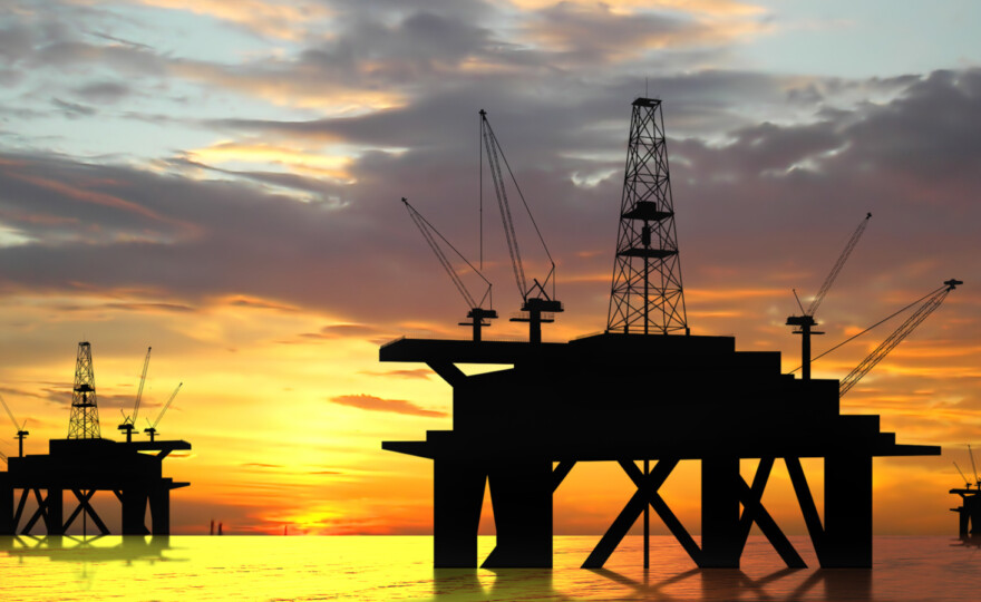 Oil rig silhouette over orange sky