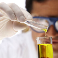 man in white coat pouring yellow liquid with into a glass