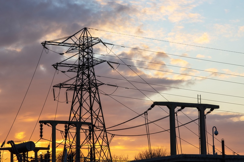 Silhouette of pylon and substation against a warm sunset sky. High Quality Image