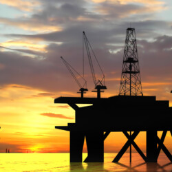 Oil rig silhouette over orange sky