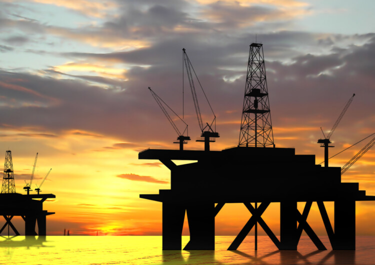 Oil rig silhouette over orange sky
